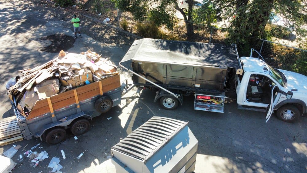 MC Junk Removal truck and loaded debris trailer on a real hauling job